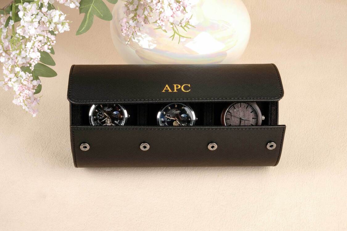 Black watch case with three watches on a beige surface, featuring the brand 'APC'.