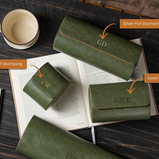 Green leather wallets with gold and silver foiling on an open book