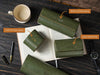 Green leather wallets with gold and silver foiling on an open book